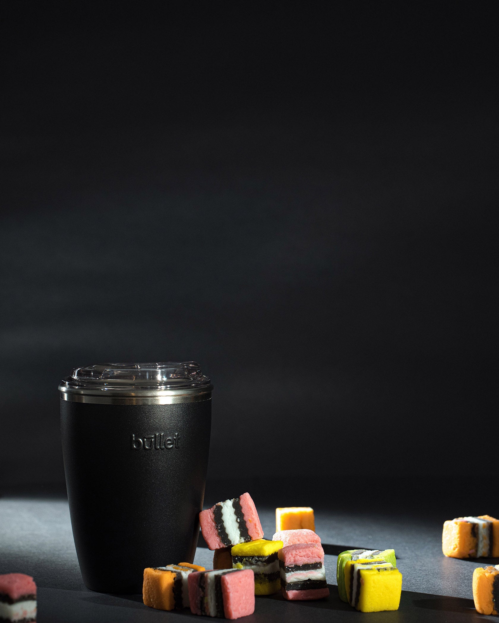 8oz black reusable coffee cup, surrounded by liquorice all sorts