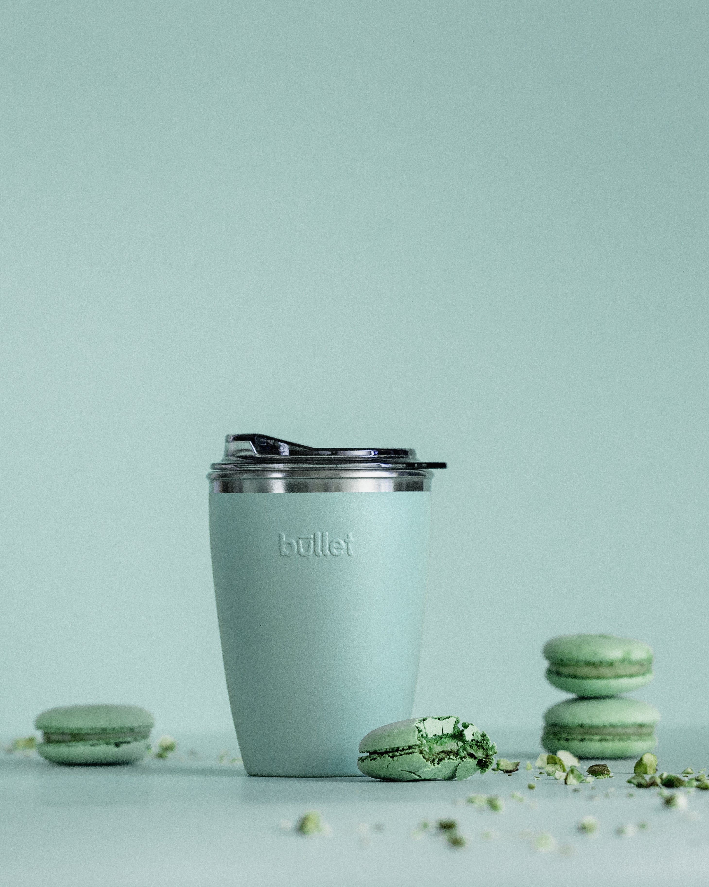 8oz green bullet cup surrounded by green macarons