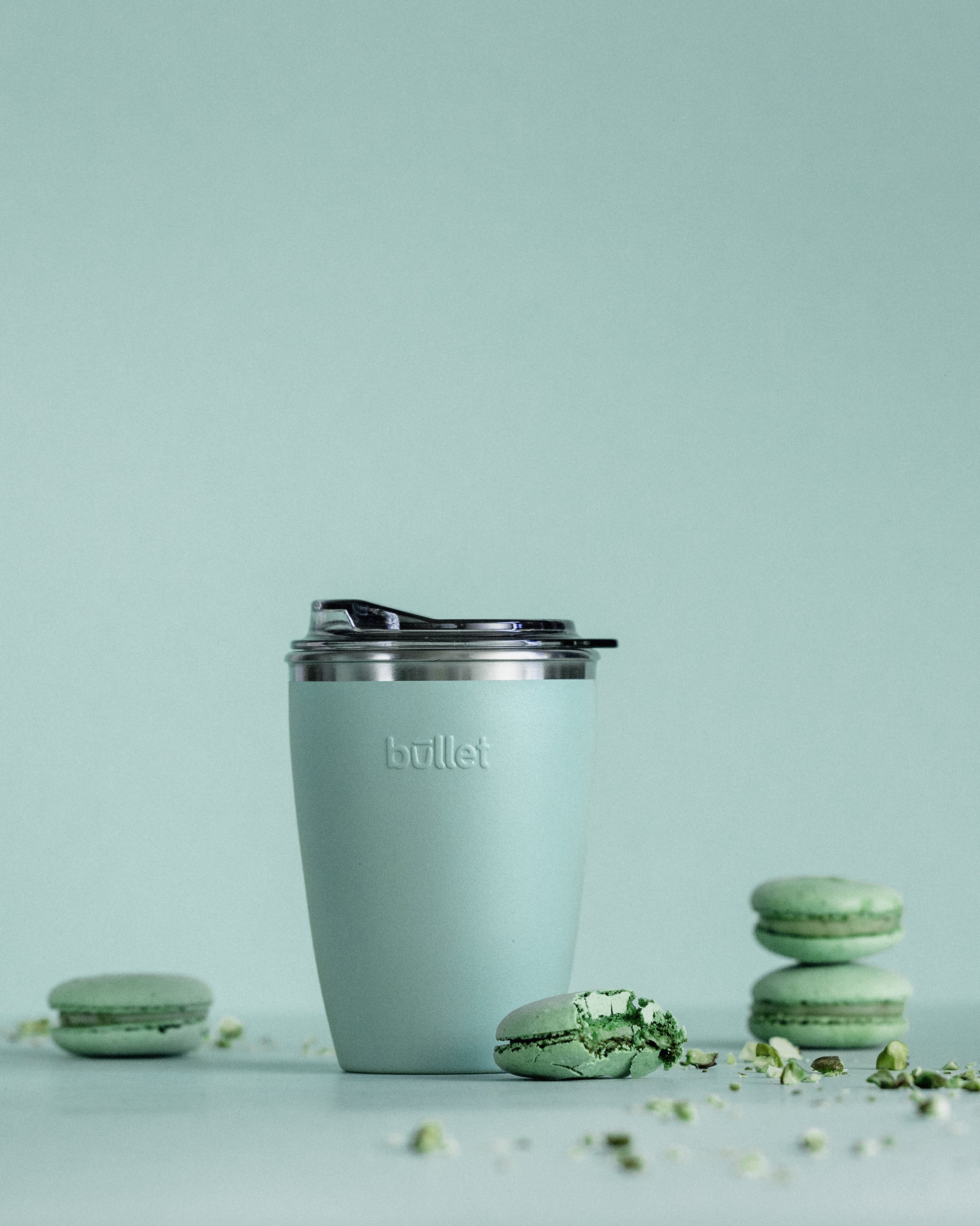 8oz green bullet cup surrounded by green macarons 