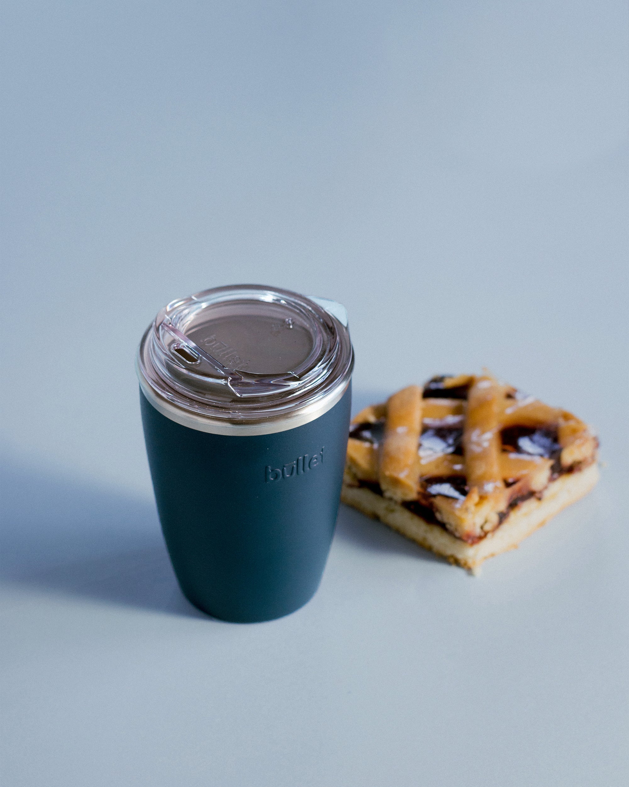8oz blue reusable coffee cup next to blueberry slice